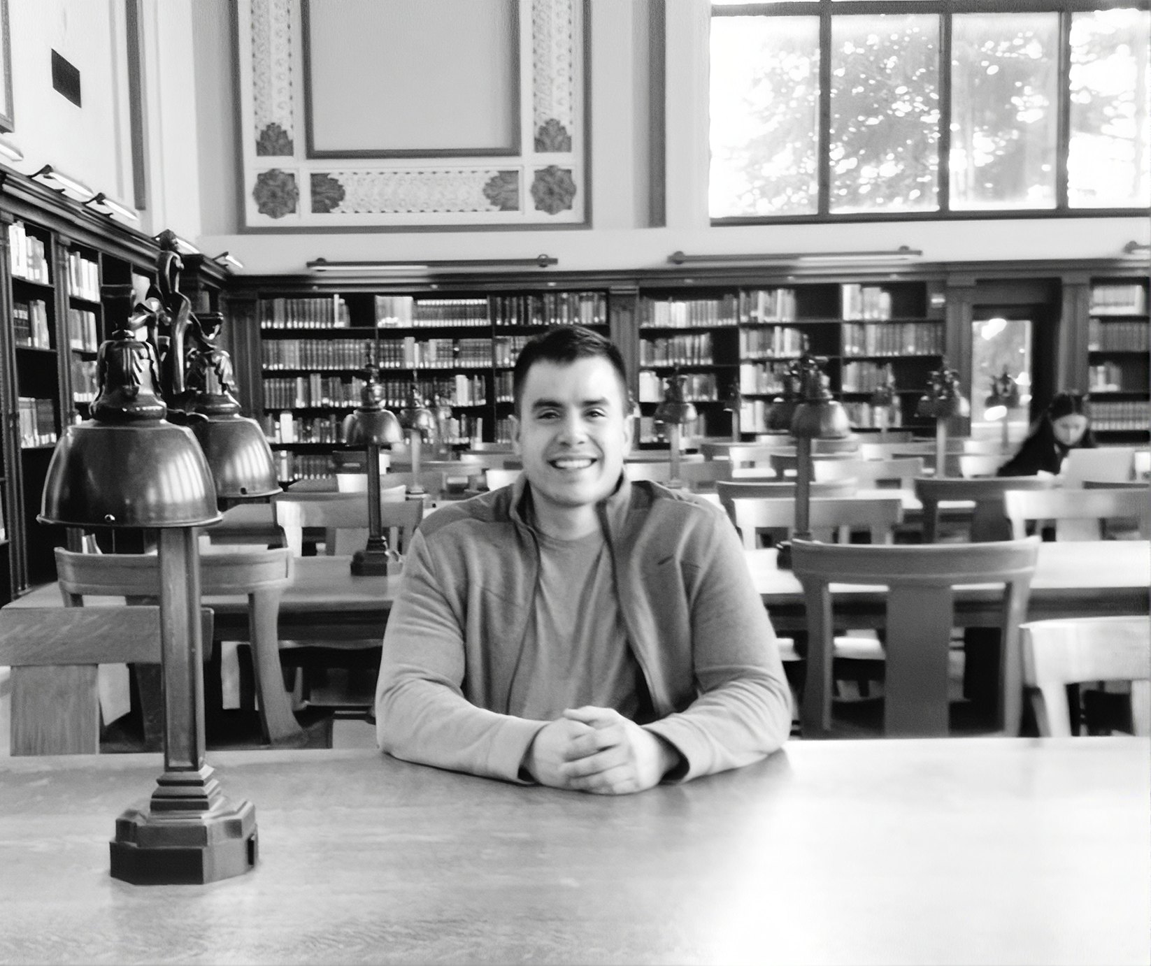 Marcos Mena-Brena sitting at a reading-room table in a university library